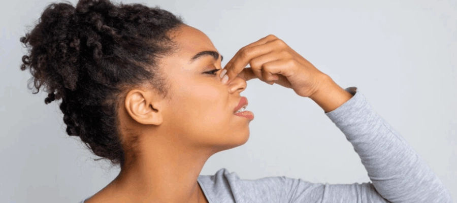 mulher de perfil tocando o nariz na região entre os olhos