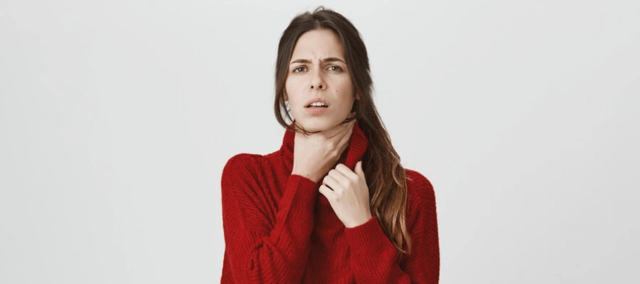 mulher com blusa vermelha e as mãos na garganta com laringite