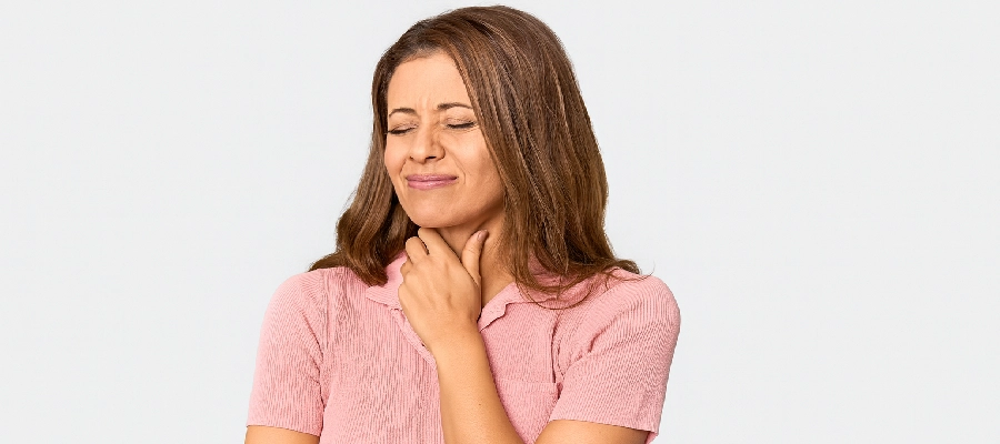 mulher com dor de garganta coloca as mãos nos dois lados do pescoço 