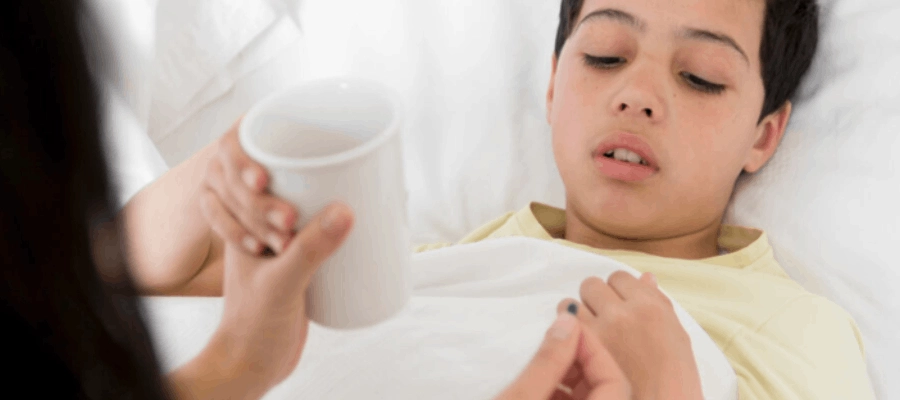 menino doente com sintomas de febre reumática sendo medicado em casa