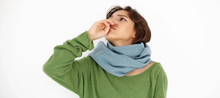 mulher com blusa verde e cachecol olha para cima com a mão no nariz