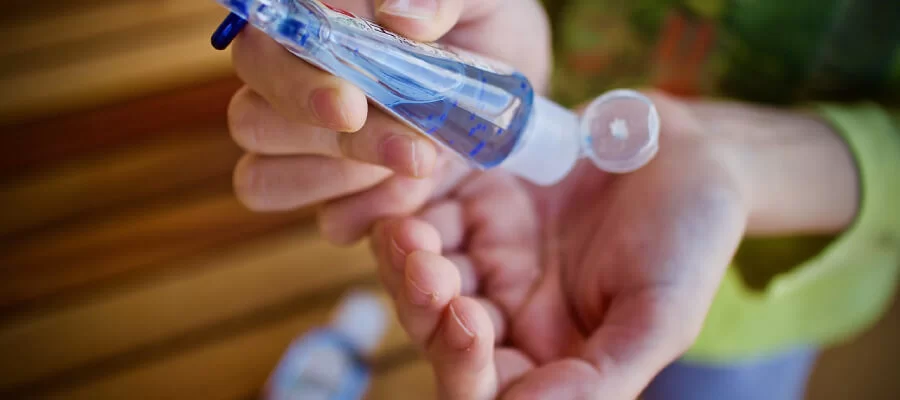 uma pessoa aplicando álcool em gel em suas mãos