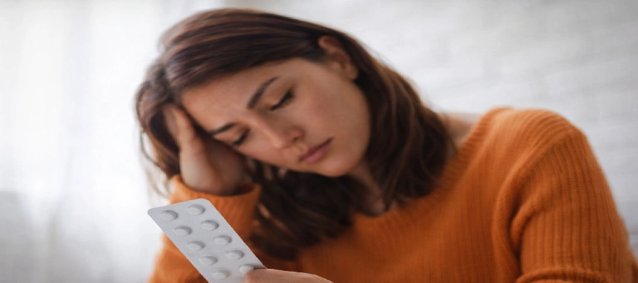 mulher doente em dúvida se dipirona serve para garganta inflamada segurando uma cartela de remédios 