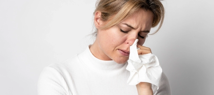 Mulher limpa o nariz com lenço em meio ao tratamento da rinite alérgica