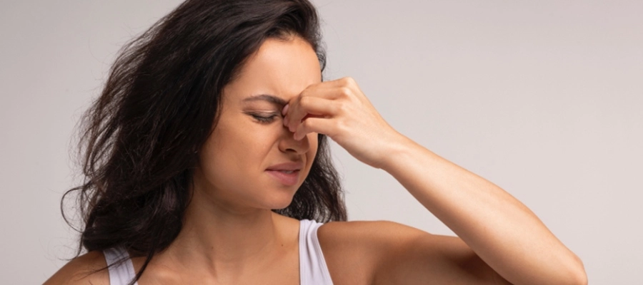 Mulher com expressão de incômodo por causa do nariz entupido e dor nos seios da face