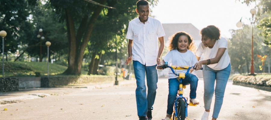 criança anda de bicicleta com os pais