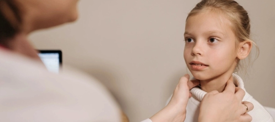 criança com sintomas de amigdalite sendo examinada por médica