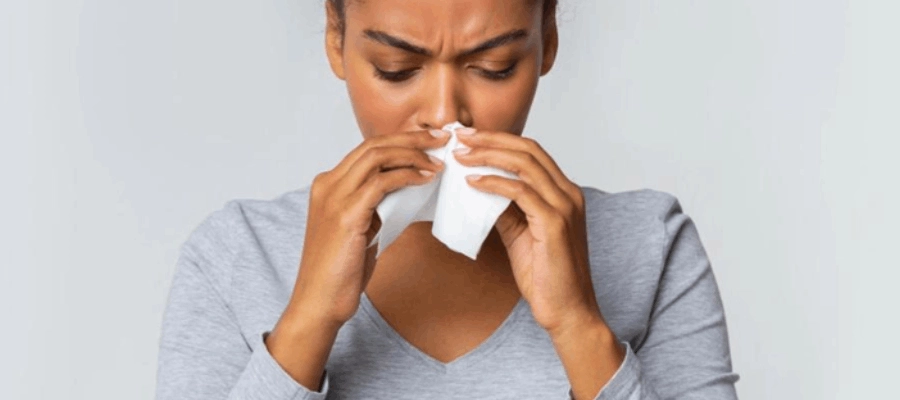 mulher assoando o nariz enquanto se pergunta como saber se está com sinusite
